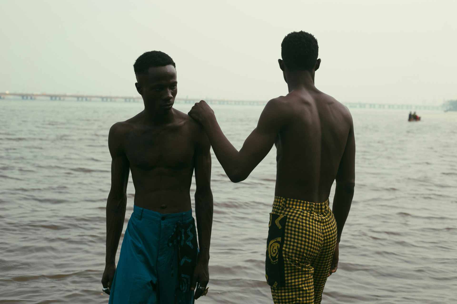 Two brothers standing at the water's edge at dusk